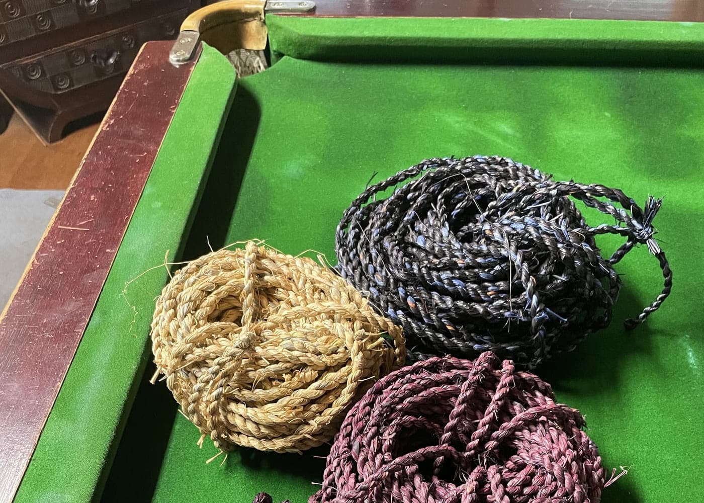 Coiled skeins of hand-dyed cord laid out on green baize