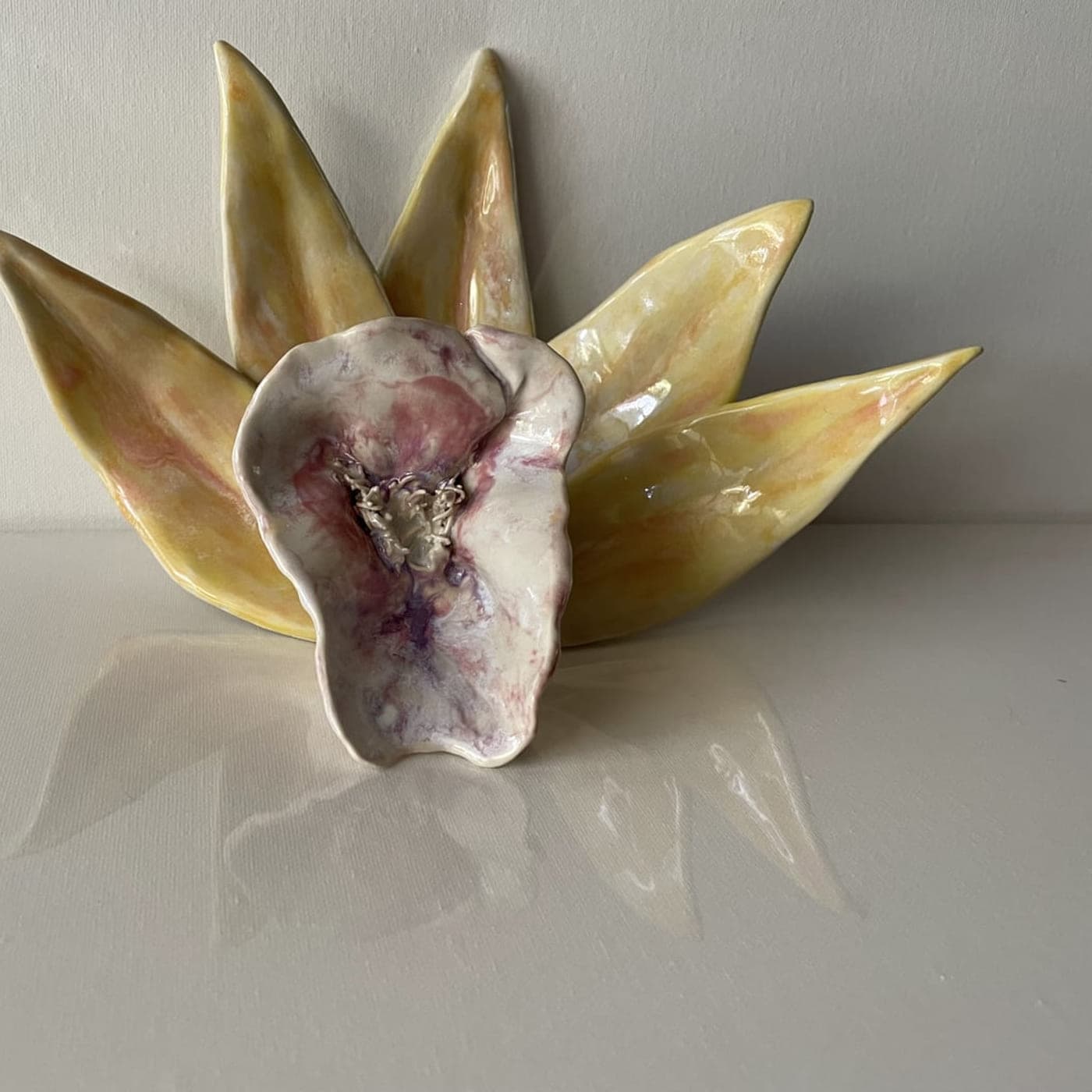 Ceramic flower form with yellow-green petals opening around a mottled violet centre