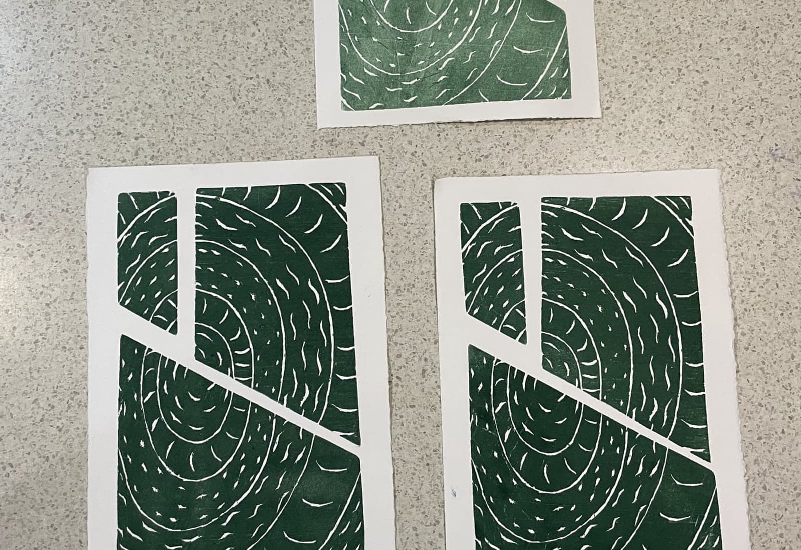 Three green geometric prints laid out on a bench