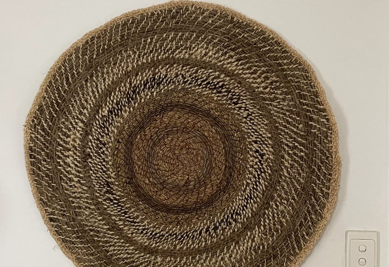 A large flat coiled mat hung on a wall