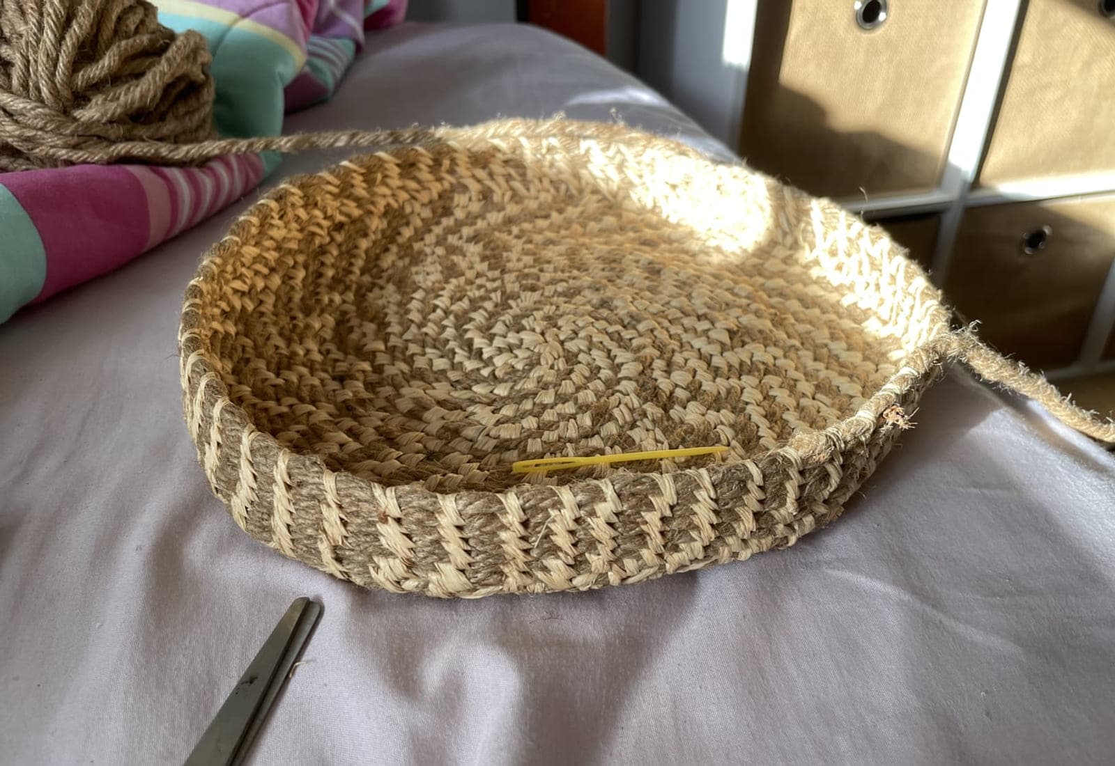 A coiled tray in progress with a stitching needle resting on it